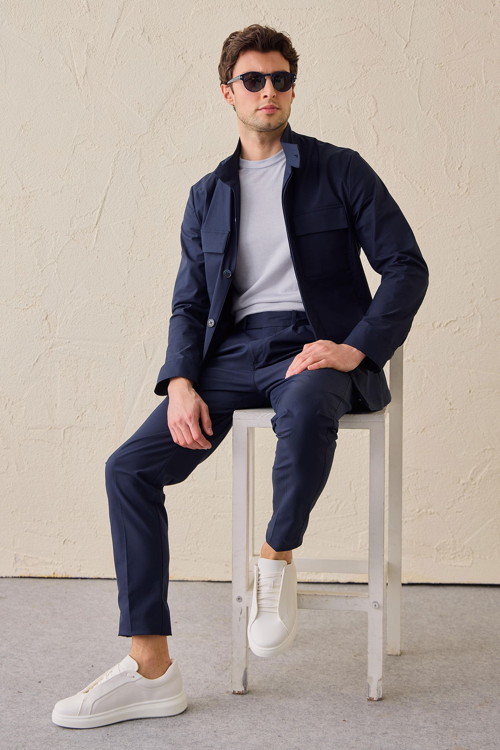 Costume deux pièces bleu marine pour homme, style safari, col montant, coupe élégante et décontractée.