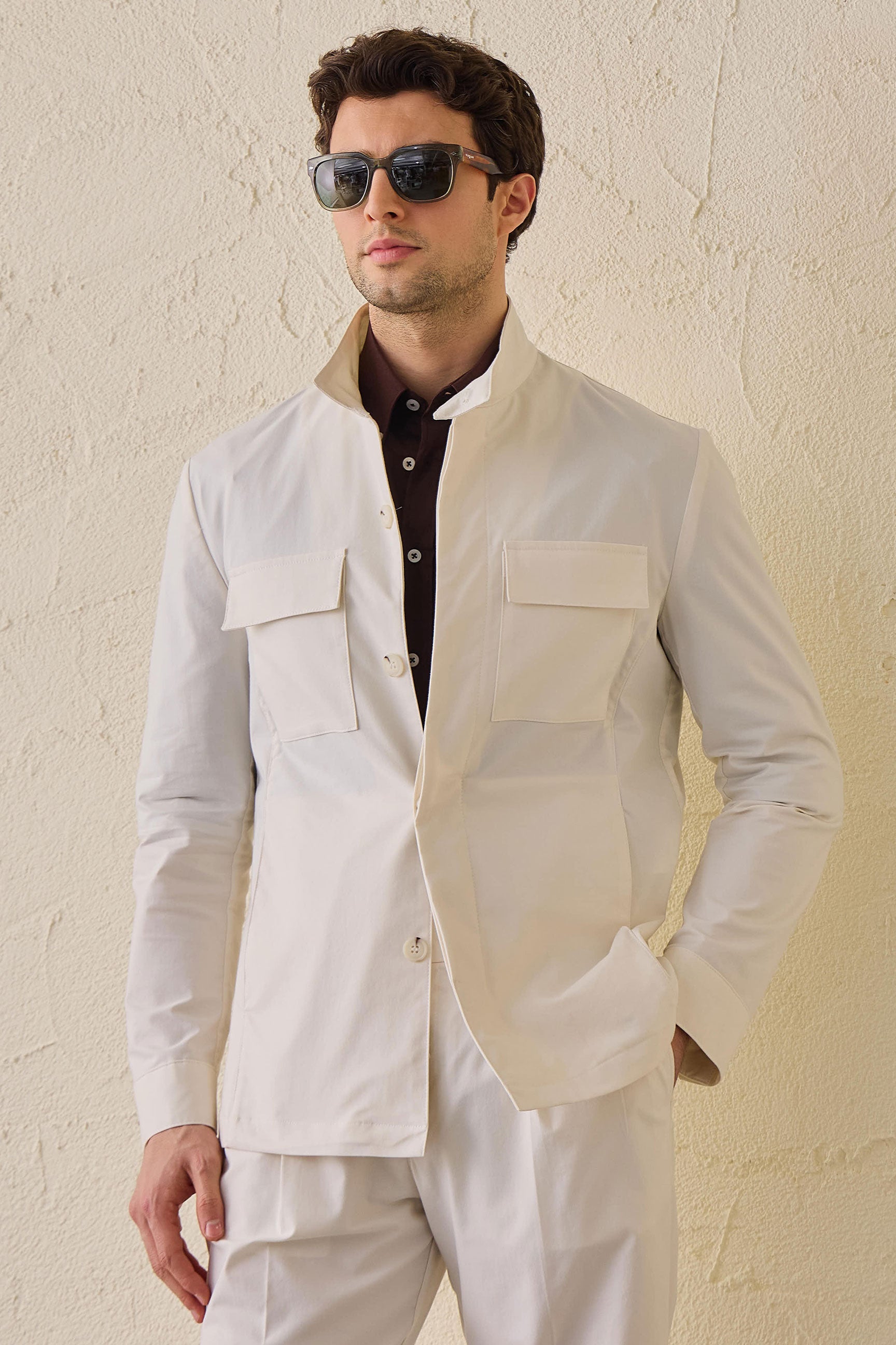 Costume deux pièces blanc pour homme, style safari, col montant, coupe élégante et décontractée.