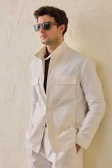 Costume deux pièces blanc pour homme, style safari, col montant, coupe élégante et décontractée.