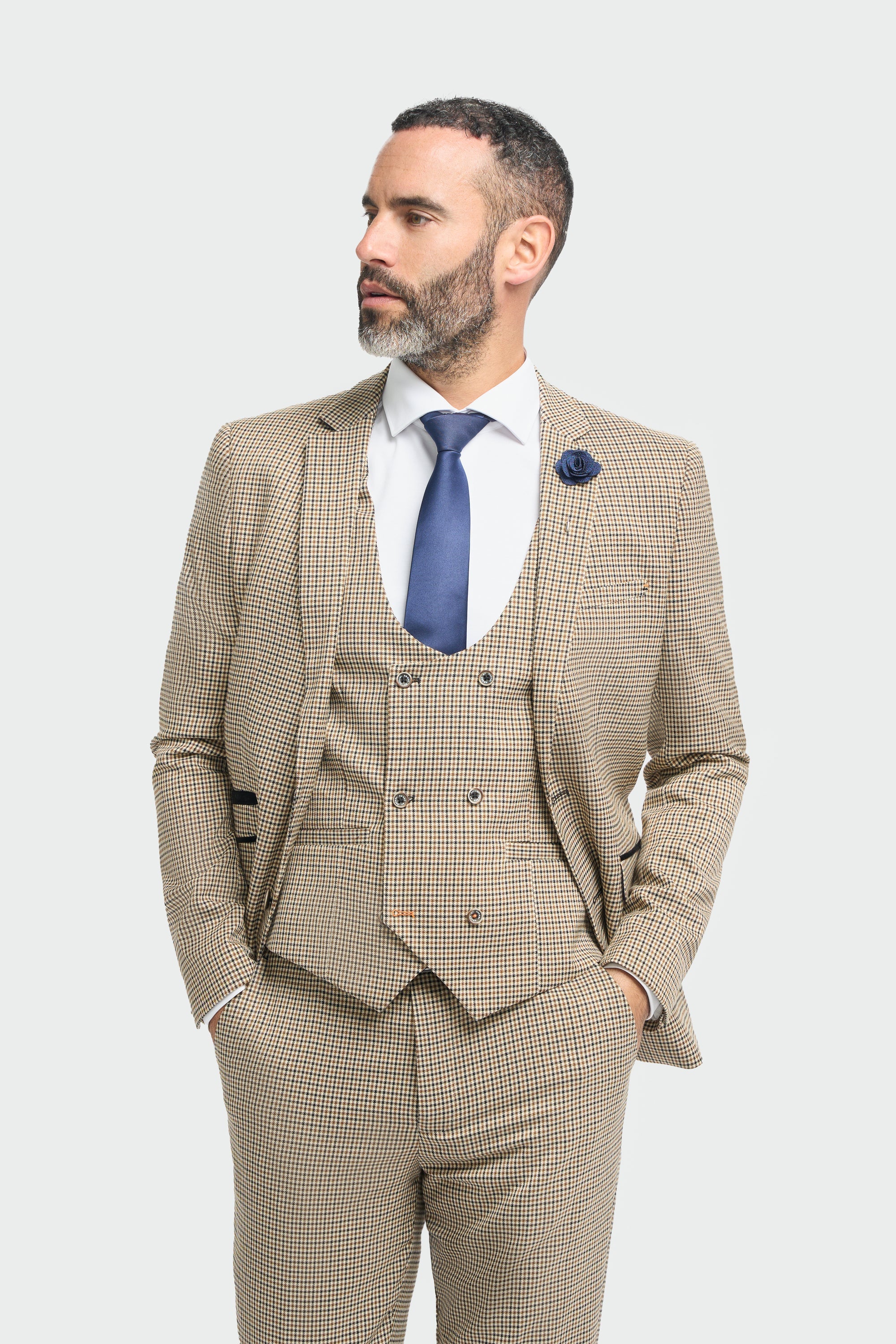 Man wearing a beige checkered suit with a blue tie on a white background